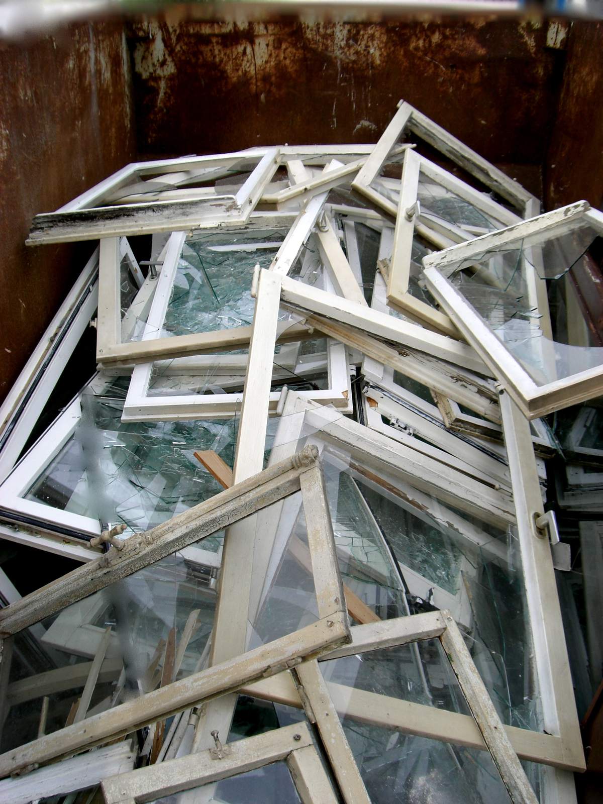 Container vol uitgebroken oude houten ramen met glas, afgevoerd na een raamvervanging